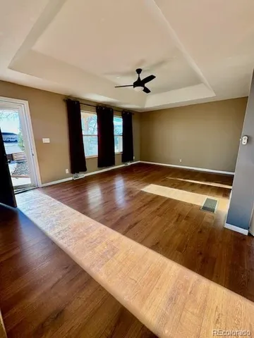 a view of an empty room with window and wooden floor