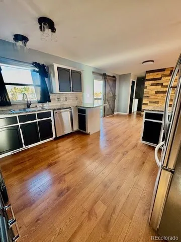 a large kitchen with a stove wooden floor and cabinets