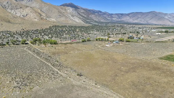 a view of a dry field with mountains in the background