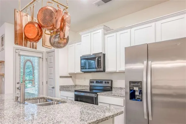 a kitchen with stainless steel appliances granite countertop a refrigerator a stove and a sink with wooden floor