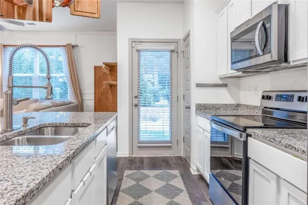 a kitchen with granite countertop a sink stove and cabinets