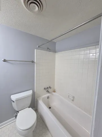 a white toilet sitting next to a bath tub