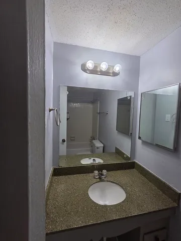 a bathroom with a granite countertop sink and a mirror