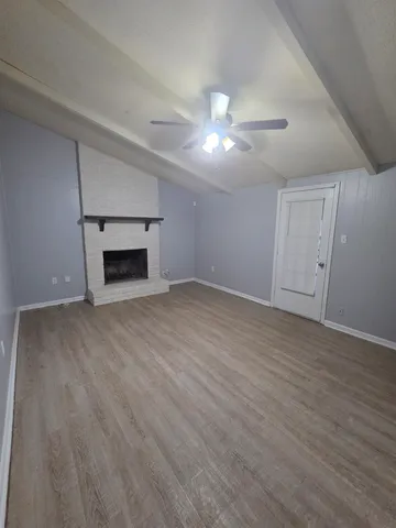 an empty room with wooden floor a fireplace and windows