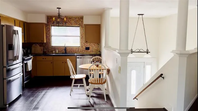 a kitchen with stainless steel appliances granite countertop a refrigerator a sink dishwasher a stove and a dining table with wooden floor