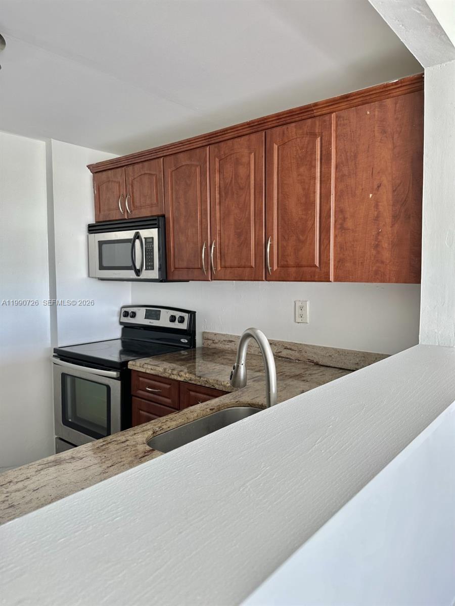 9001 Southwest 77th Avenue, Unit C604 Miami, FL 33156 - Photo 6 of 17 a kitchen with stainless steel appliances granite countertop a sink stove and microwave