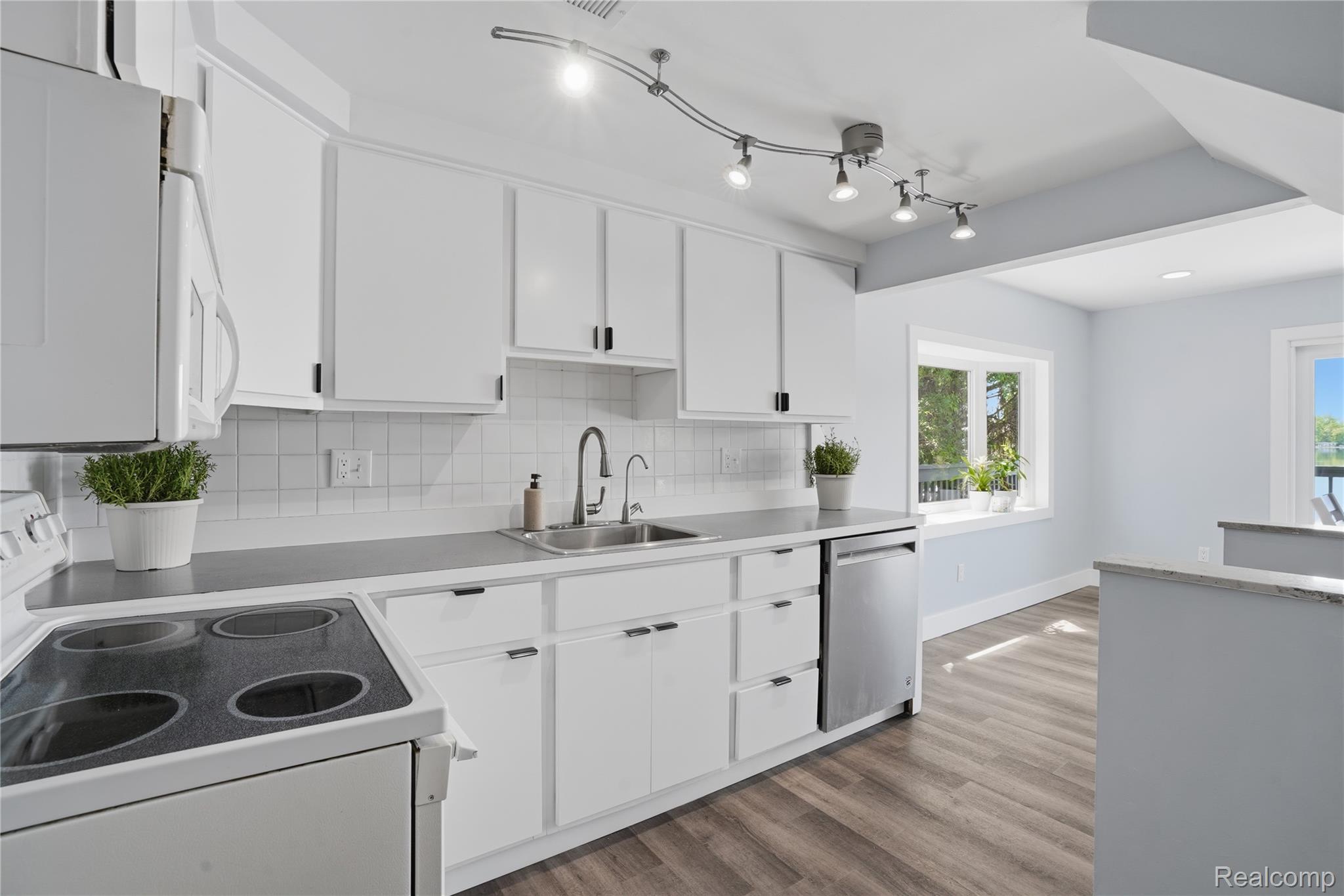 7217 Andersonville Road Clarkston, MI 48346 - Photo 14 of 65 Kitchen featuring white cabinetry with dark hardware, a stainless steel sink, and light gray countertops