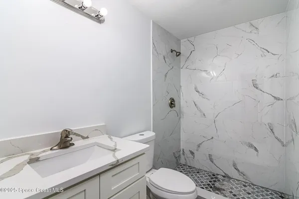 a bathroom with a granite countertop sink toilet a mirror and shower