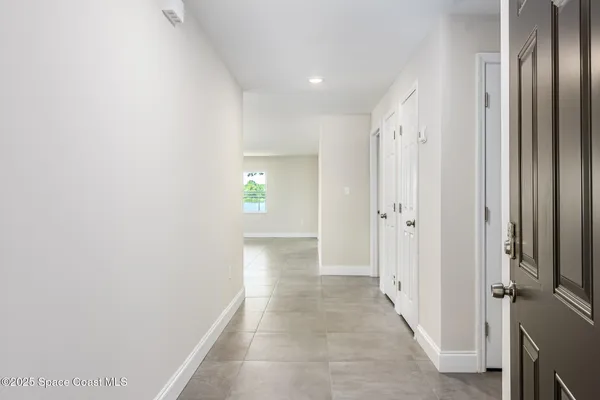 a view of a hallway with wooden floor and a bathroom