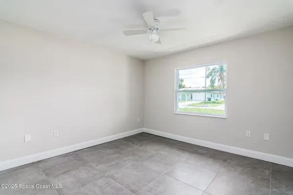 an empty room with windows and ceiling fan