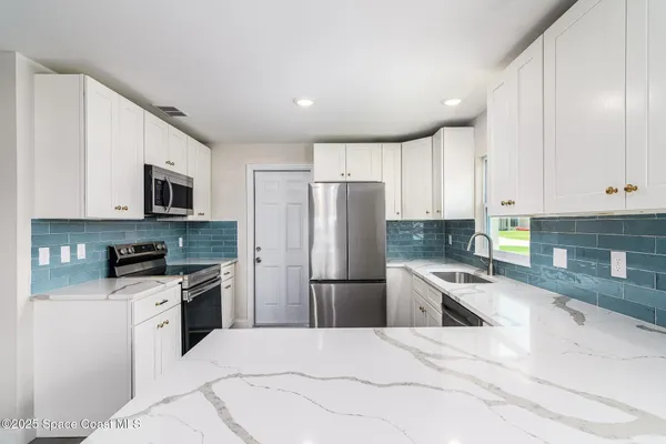 a kitchen with granite countertop a refrigerator stove top oven and sink