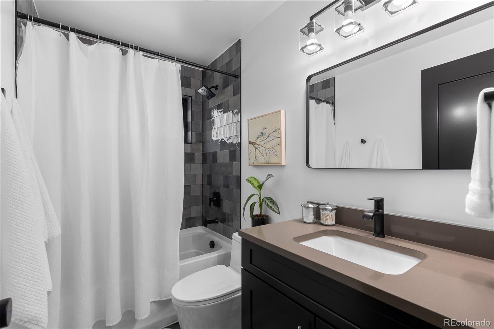 1655 Wolff Street Denver, CO 80204 - Photo 29 of 50 a bathroom with a granite countertop sink vanity mirror and shower