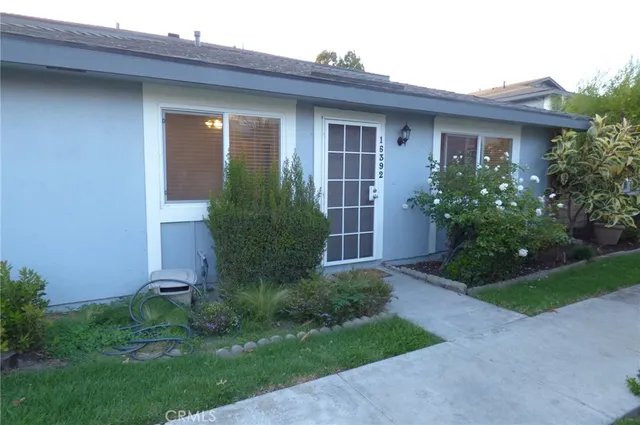 a view of a house with brick walls and a yard with plants