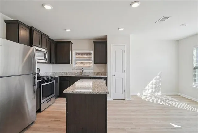 a kitchen with granite countertop a refrigerator stove and oven