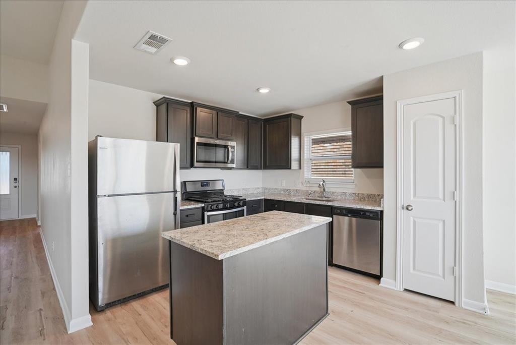 115 Sammy Fowler Avenue Venus, TX 76084 - Photo 16 of 34 a kitchen with stainless steel appliances granite countertop a refrigerator a sink a stove a microwave and island