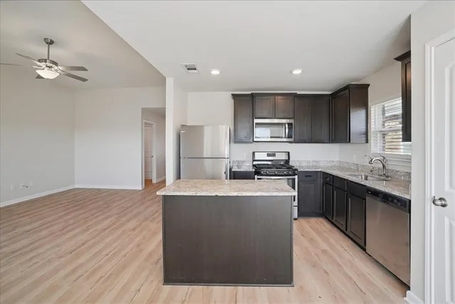 a large kitchen with stainless steel appliances granite countertop a stove a sink dishwasher and a refrigerator with wooden floor