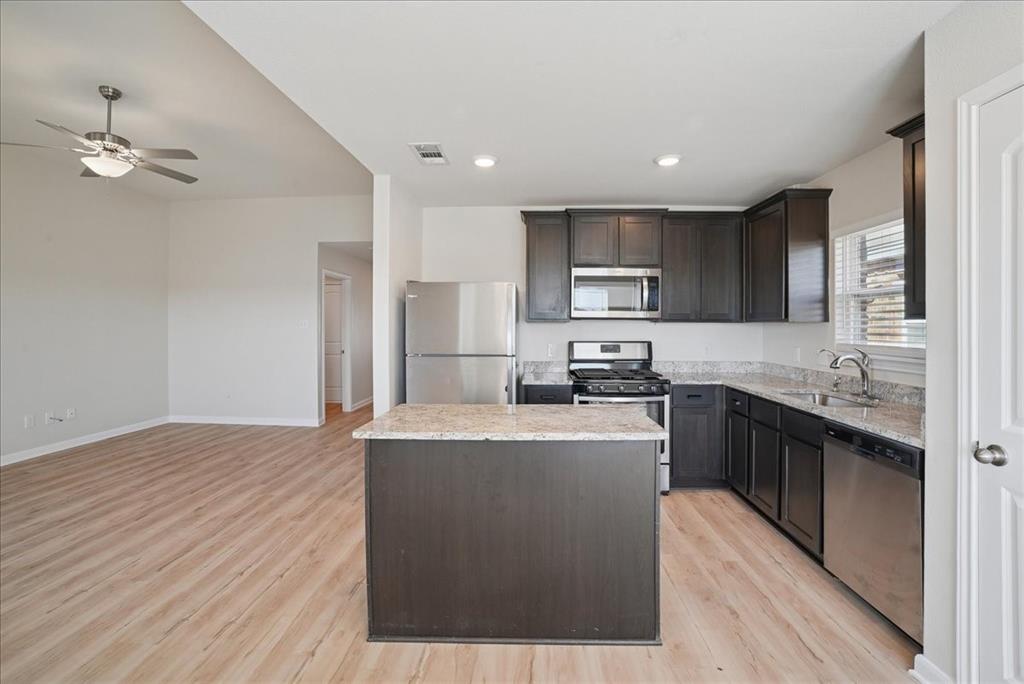 115 Sammy Fowler Avenue Venus, TX 76084 - Photo 17 of 34 a large kitchen with stainless steel appliances granite countertop a stove a sink dishwasher and a refrigerator with wooden floor