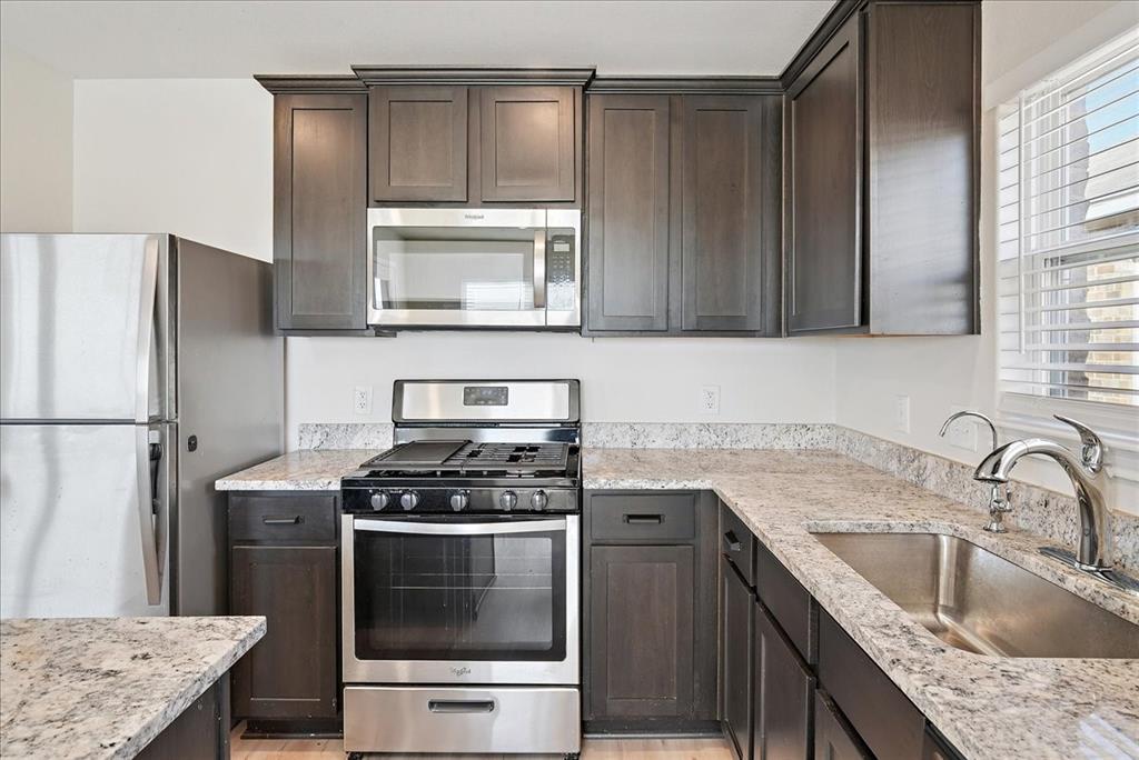 115 Sammy Fowler Avenue Venus, TX 76084 - Photo 19 of 34 a kitchen with granite countertop a sink stove and refrigerator
