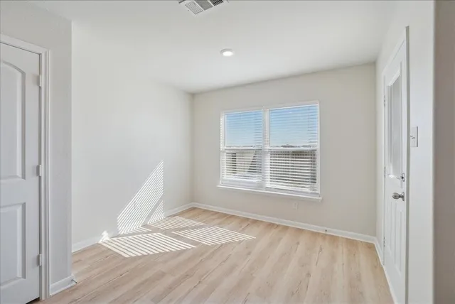 a view of an empty room with wooden floor and a window
