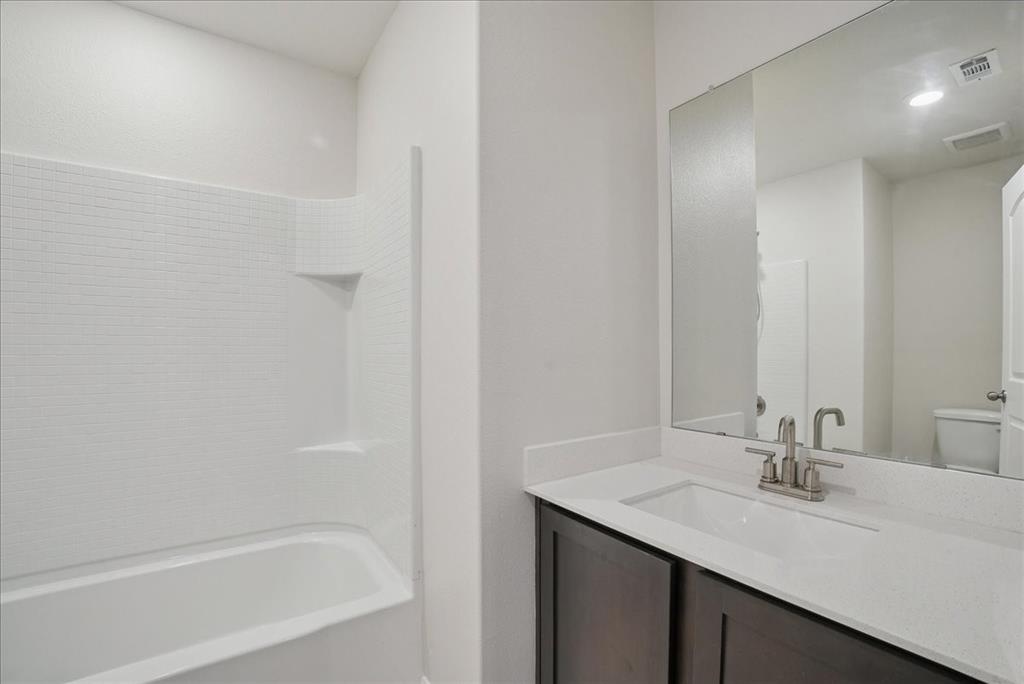 115 Sammy Fowler Avenue Venus, TX 76084 - Photo 5 of 34 a bathroom with a bathtub sink vanity and a mirror