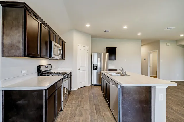 a kitchen with a sink stove top oven and refrigerator