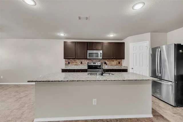 a kitchen with stainless steel appliances granite countertop a refrigerator a sink a stove a microwave and white cabinets