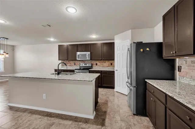 a kitchen with stainless steel appliances granite countertop a sink refrigerator and microwave