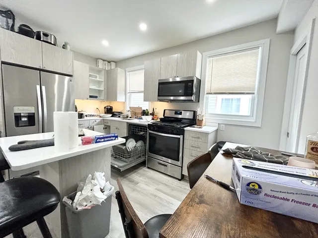 a kitchen that has a microwave a stove a sink and a dining table with granite countertop wooden floor