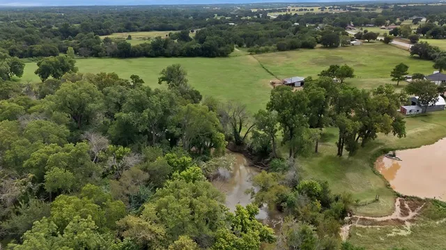 an aerial view of a houses with outdoor space and trees all around