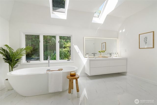 a bathroom with a white tub a sink and a large window