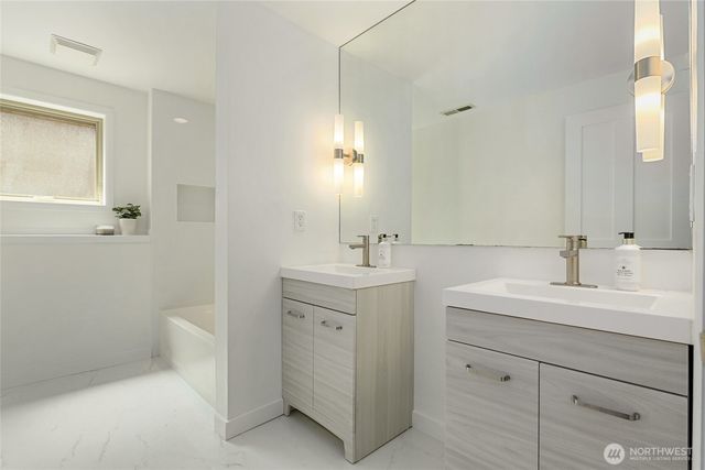 a bathroom with a double vanity sink and mirror with toilet