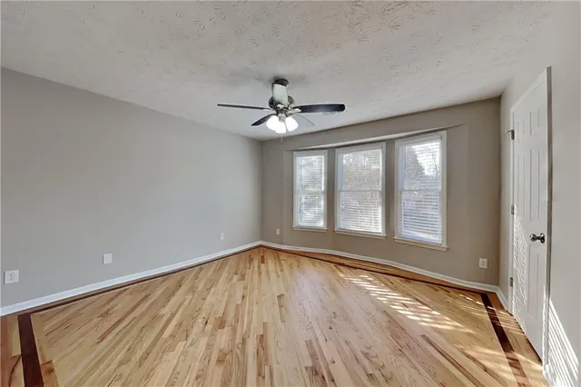 a view of an empty room with a window and wooden floor