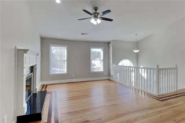 a view of an empty room with a window and wooden floor