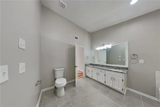 a bathroom with a granite countertop toilet a sink and a mirror
