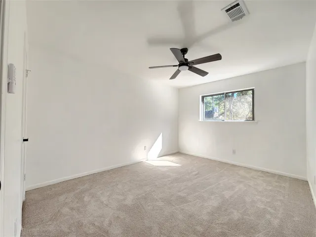 an empty room with a window and a fan