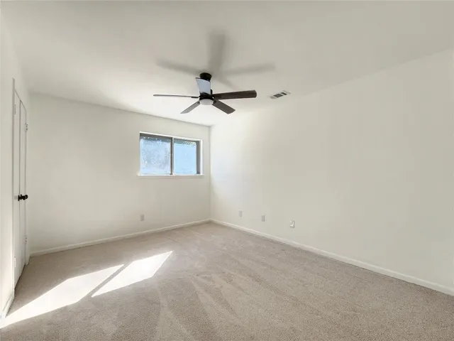 an empty room with a ceiling fan and a window