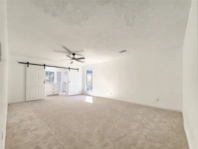 an empty room with windows and fan