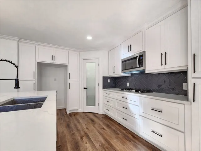 a kitchen with kitchen island granite countertop a sink cabinets and stainless steel appliances