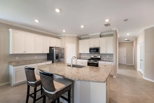 a kitchen with granite countertop a table chairs microwave and refrigerator