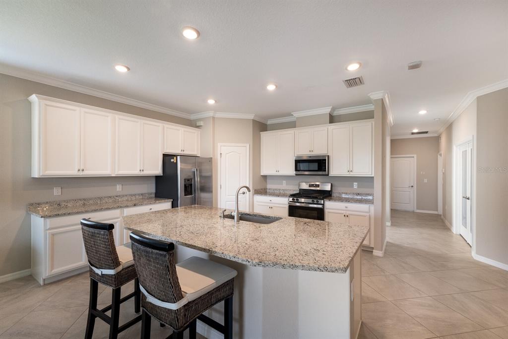 2607 Avolet Court Lakewood Ranch, FL 34211 - Photo 9 of 47 a kitchen with granite countertop a table chairs microwave and refrigerator
