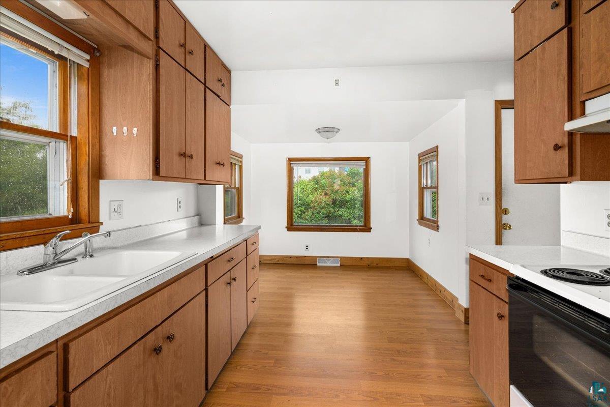 424 East Upham Road Duluth, MN 55811 - Photo 5 of 38 Kitchen featuring wood-finish flooring, white countertops, wood cabinetry, and a range oven
