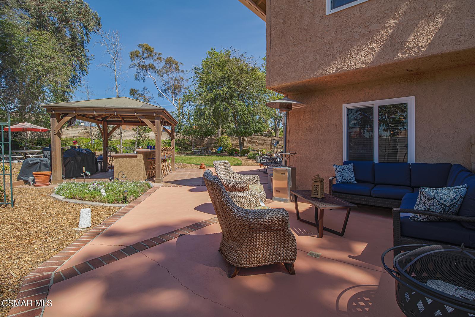 13339 Peach Hill Road Moorpark, CA 93021 - Photo 41 of 45 a view of a patio with couches table and chairs under an umbrella with a fire pit