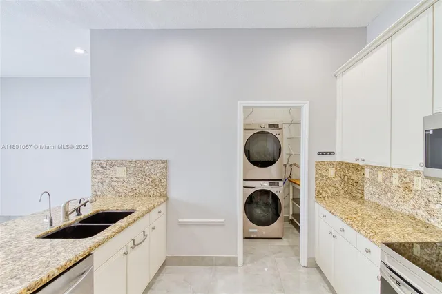 a kitchen with granite countertop a sink and white cabinets