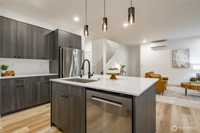 a kitchen with stainless steel appliances granite countertop a sink a refrigerator and a stove with wooden floor