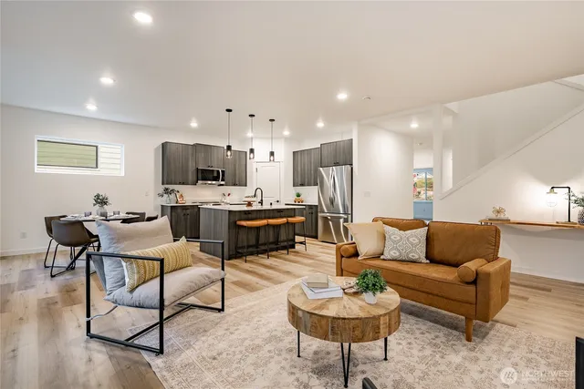 a living room with furniture kitchen view and a wooden floor