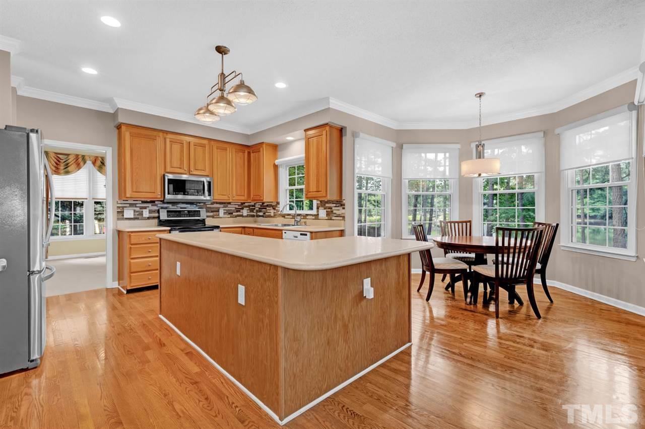 8601 Wheeling Drive Raleigh, NC 27615 - Photo 13 of 25 a kitchen with stainless steel appliances granite countertop a stove a refrigerator a kitchen island a dining table and chairs