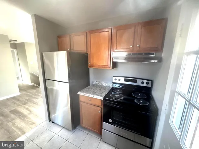 a kitchen with stainless steel appliances granite countertop a refrigerator a sink a stove with wooden cabinets