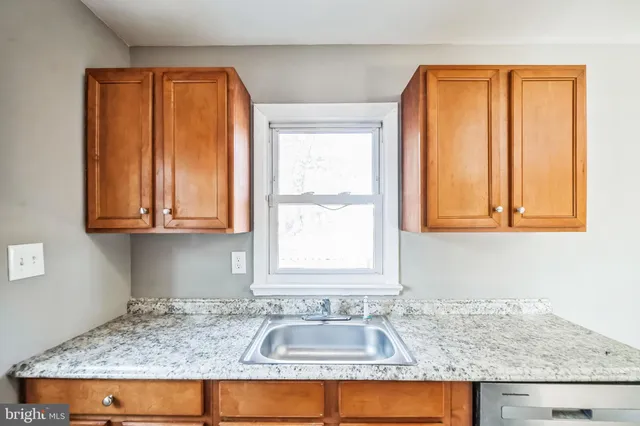 a bathroom with a granite countertop sink and a window
