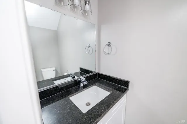 a bathroom with a granite countertop sink and cabinets