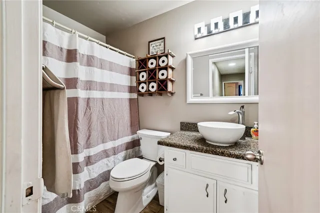 a bathroom with a granite countertop sink a toilet and a shower curtain